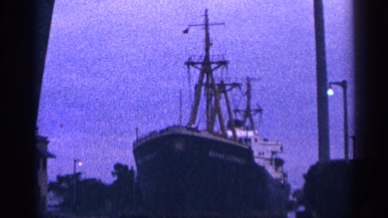 Docked ship seen closer in silhouette, with tall masts against a purple dusk sky.