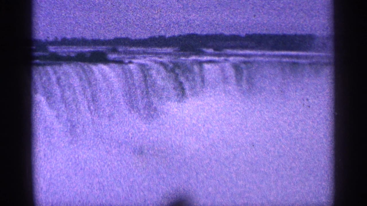 Wide view of the waterfall and rising mist with dark scan bars around the frame.