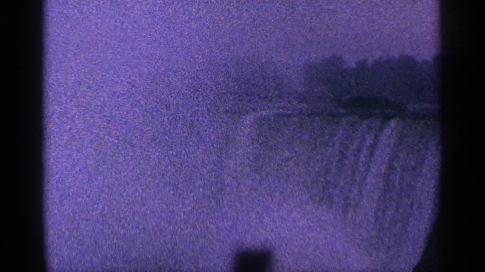 Purple-tinted 8mm view of Niagara Falls with falling water, distant dark landscape, and central film-edge obstruction.