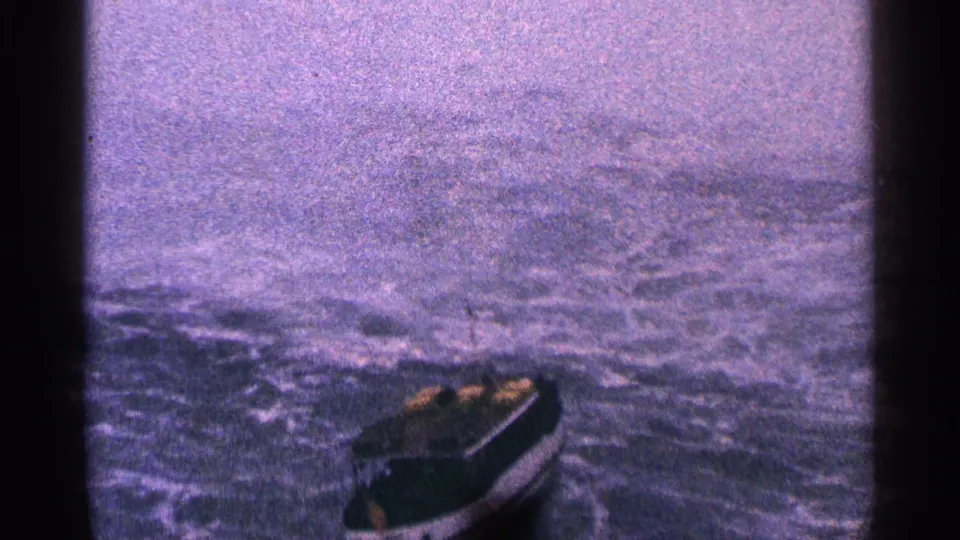 A small boat moves across turbulent Niagara River water below the falls, partly framed by mist and 8mm film gate edges.