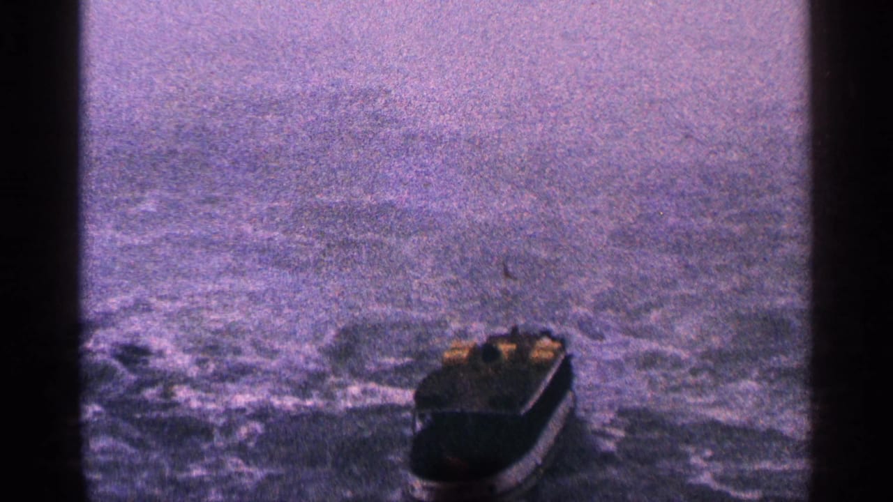 Small boat near the lower right of the frame on rough water with a hazy horizon.