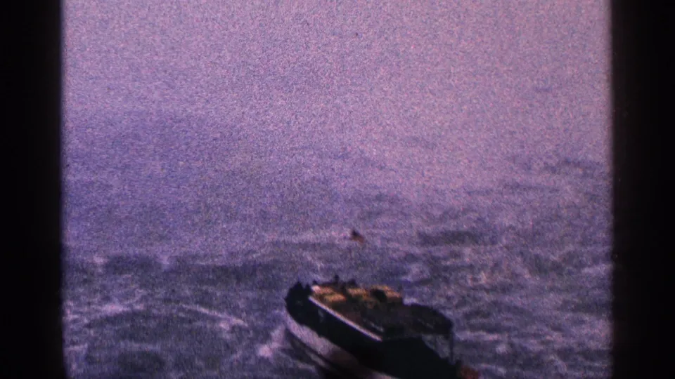 End frame shows the small boat at lower right on rough water, with 1964 8mm grain, color shift, and no readable markings or identifiable faces.