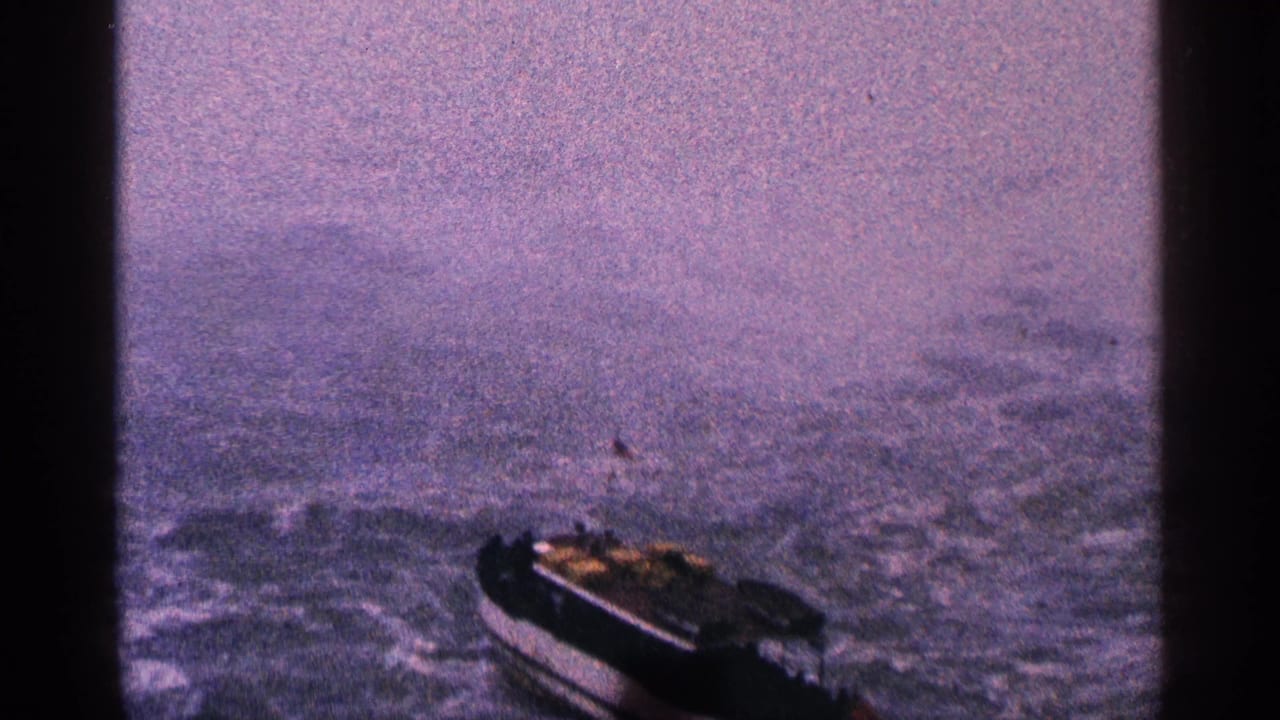 Small motorboat moving across choppy water under a hazy sky.