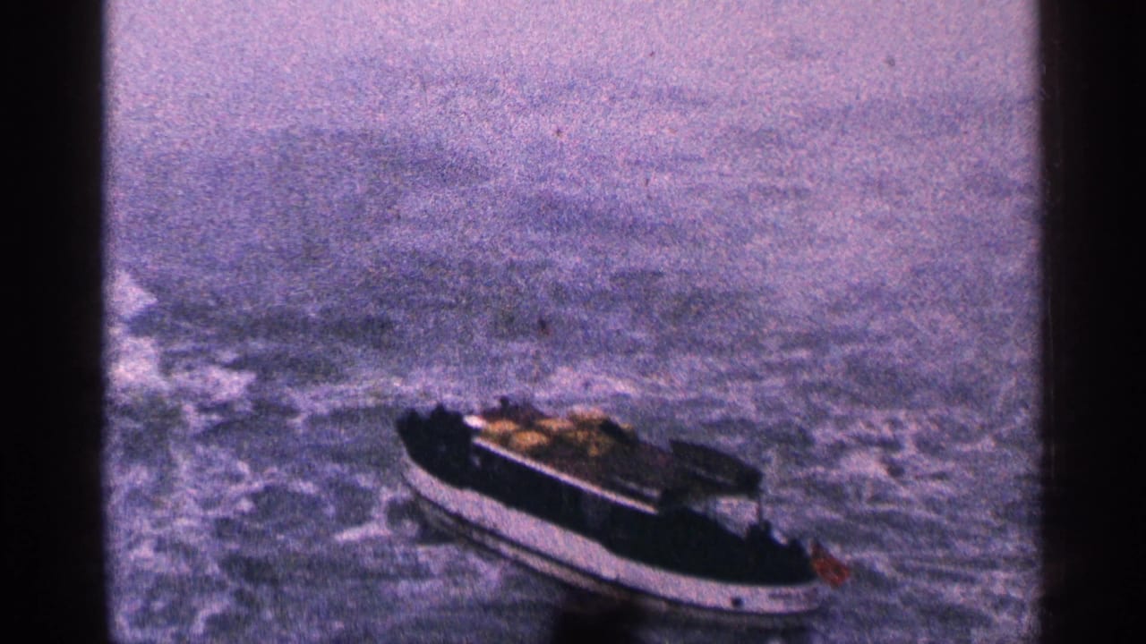 Small motorboat seen from above on rough water with wake behind it.