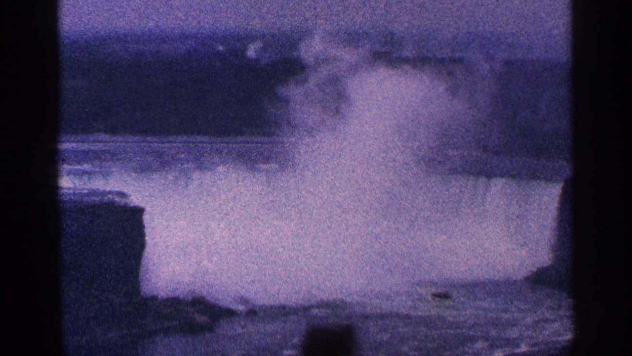 1964 8mm home-movie frame of Niagara Falls in Canada, with a large plume of mist above the water and dark borders from the film scan.