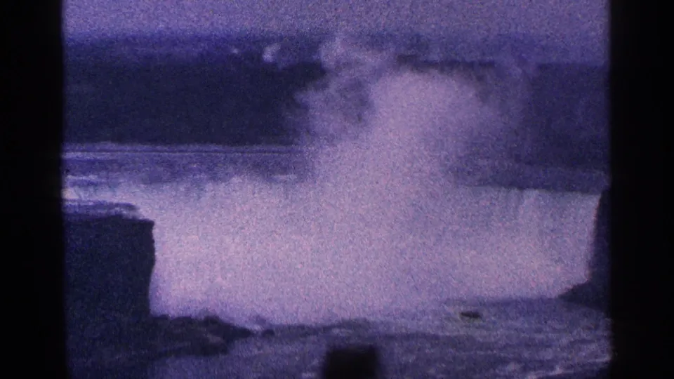 1964 8mm home-movie frame of Niagara Falls in Canada, with a large plume of mist above the water and dark borders from the film scan.
