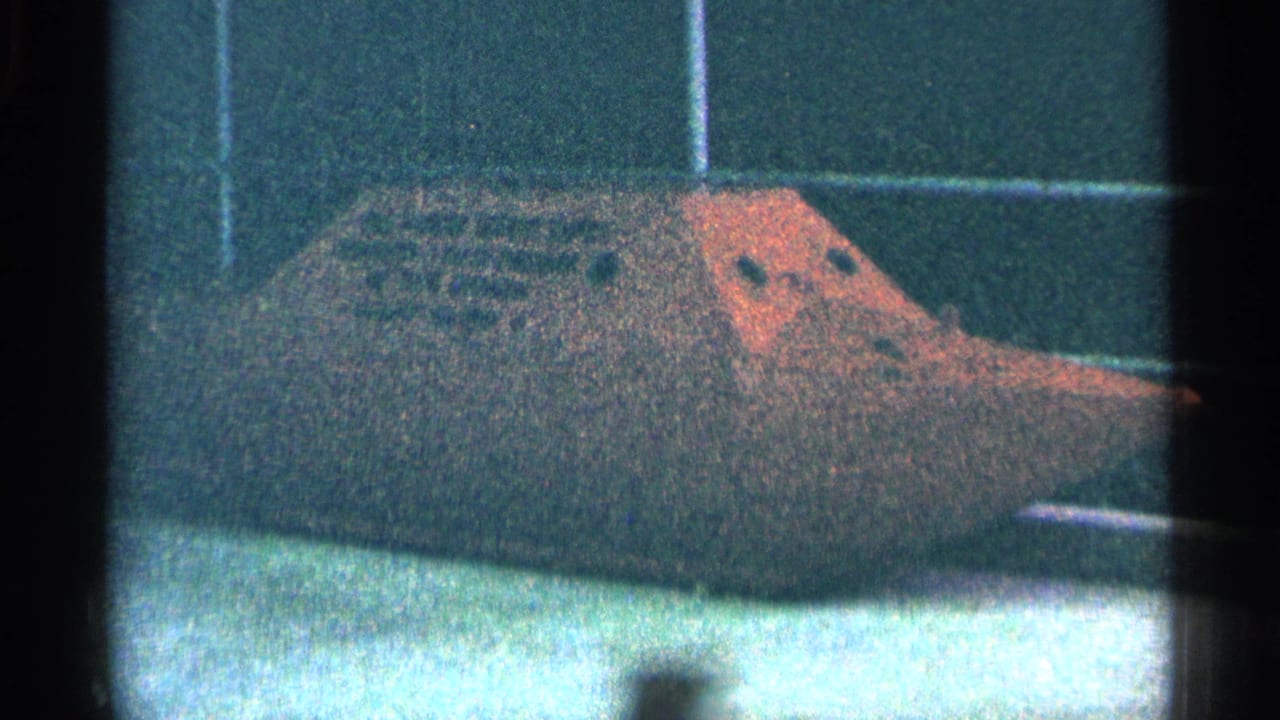 1964 Niagara Falls frame showing the same steamship model exhibit, softened by grain, color shift, and dark 8mm frame edges.