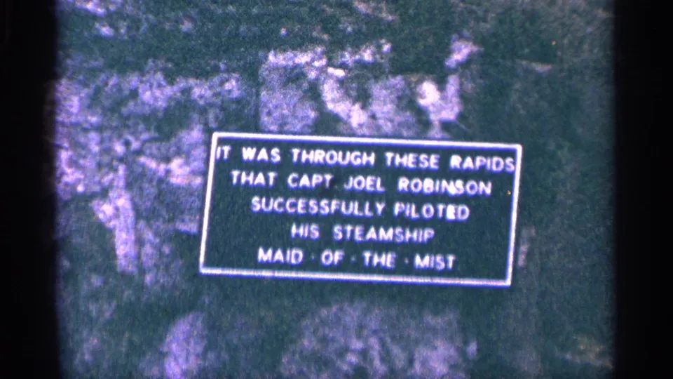 1964 Niagara Falls frame showing a bordered exhibit sign about Capt. Joel Robinson piloting Maid of the Mist through rapids.