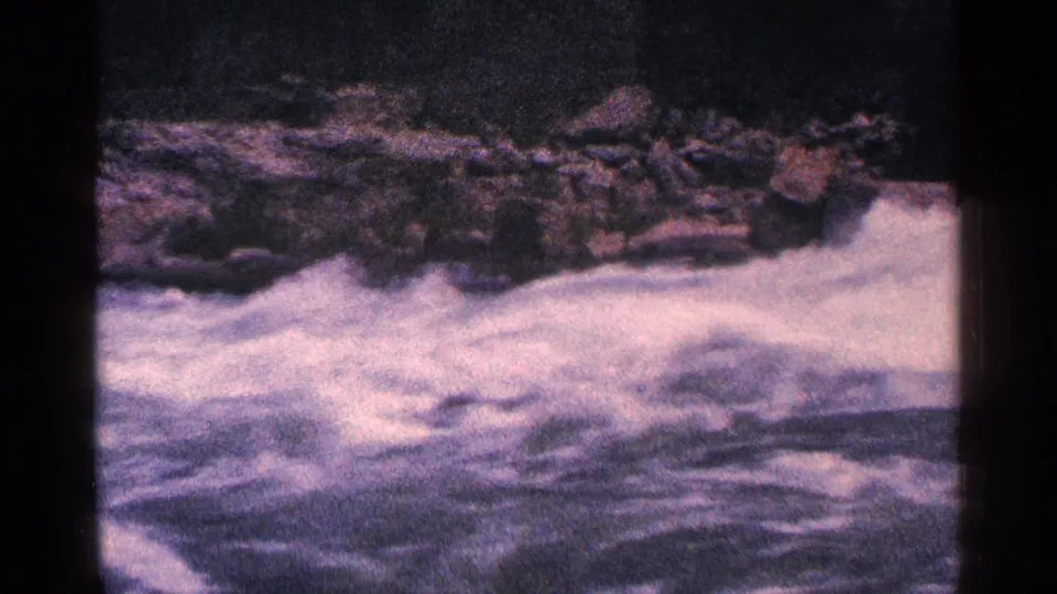 1964 8mm frame of broad white rapids and jagged rocks at Niagara Falls Canada, with faded home-movie color.
