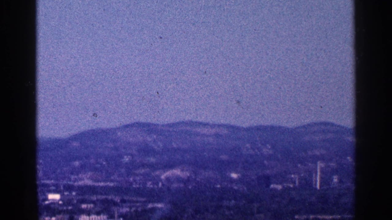 1964 8mm home-movie view of a hazy Hudson River landscape near West Point, with distant hills and heavy frame borders.