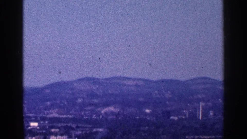 1964 8mm home-movie view of a hazy Hudson River landscape near West Point, with distant hills and heavy frame borders.