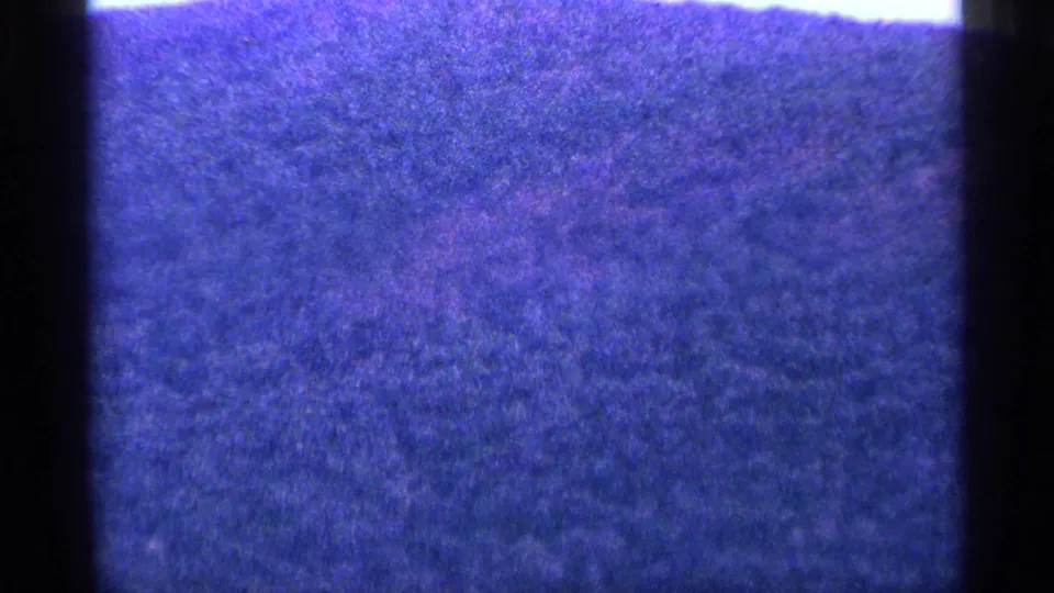 Blue-shifted 8mm frame with heavy grain, dark side borders, and only faint landscape detail visible.