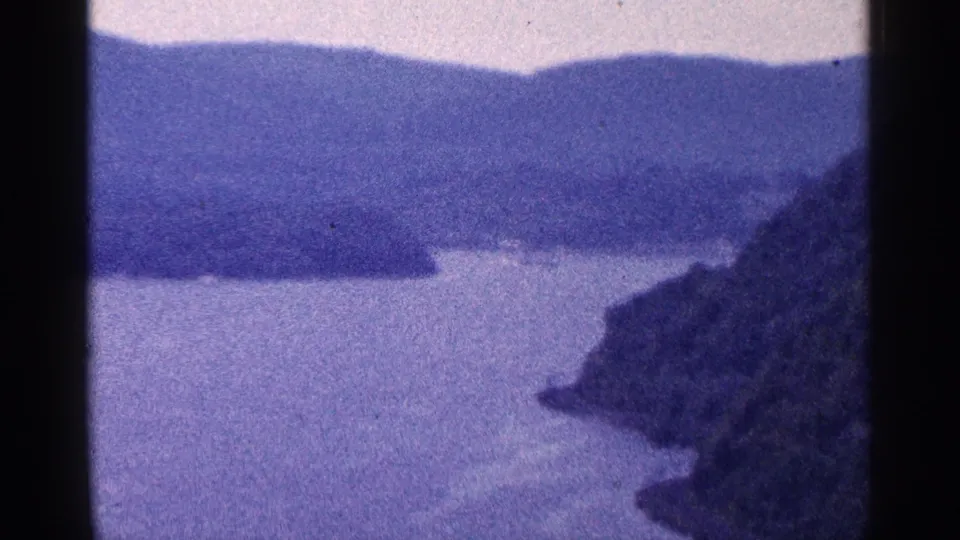 Soft 8mm scenic view near Niagara Falls, Canada, showing calm water, distant hills, and a rocky right-hand shore.