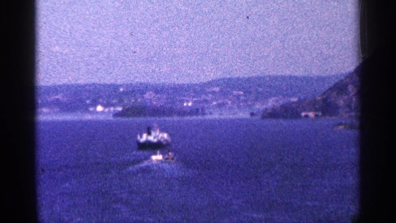 1964 Niagara Falls Canada travel footage shows boats on open water, a hazy shoreline, and dark film-frame edges.