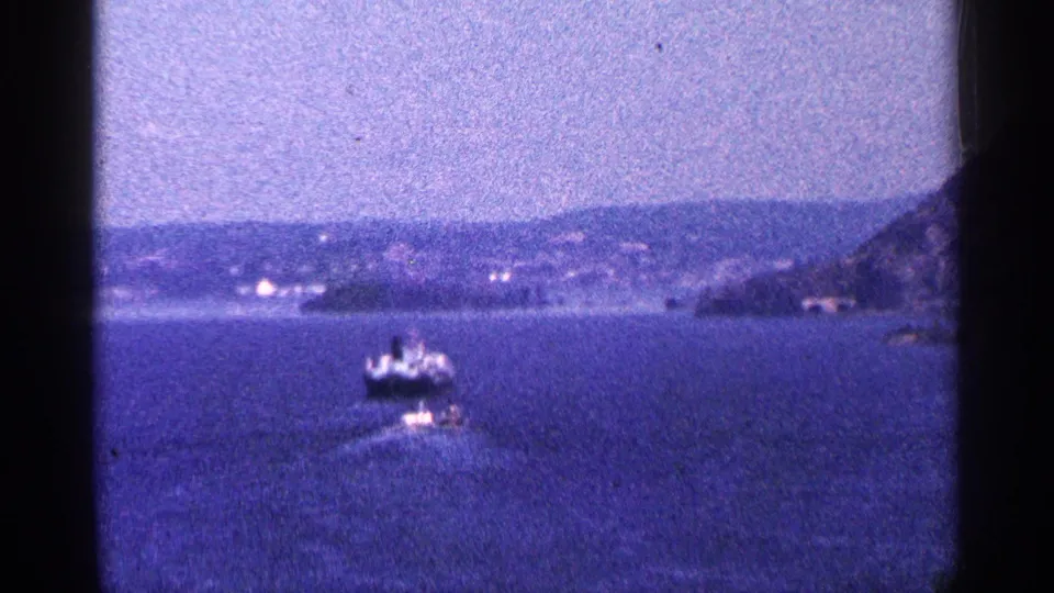 1964 Niagara Falls Canada travel footage shows boats on open water, a hazy shoreline, and dark film-frame edges.