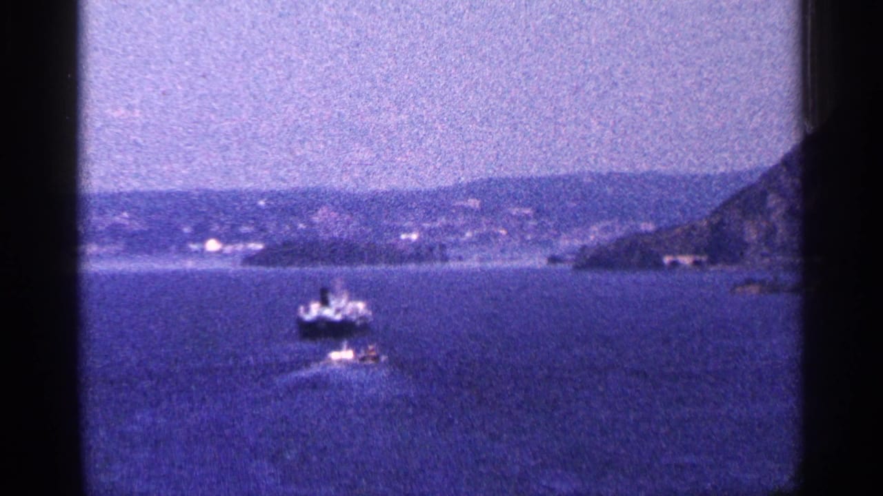 Boat on open water with shoreline, hills, and a dark frame edge.