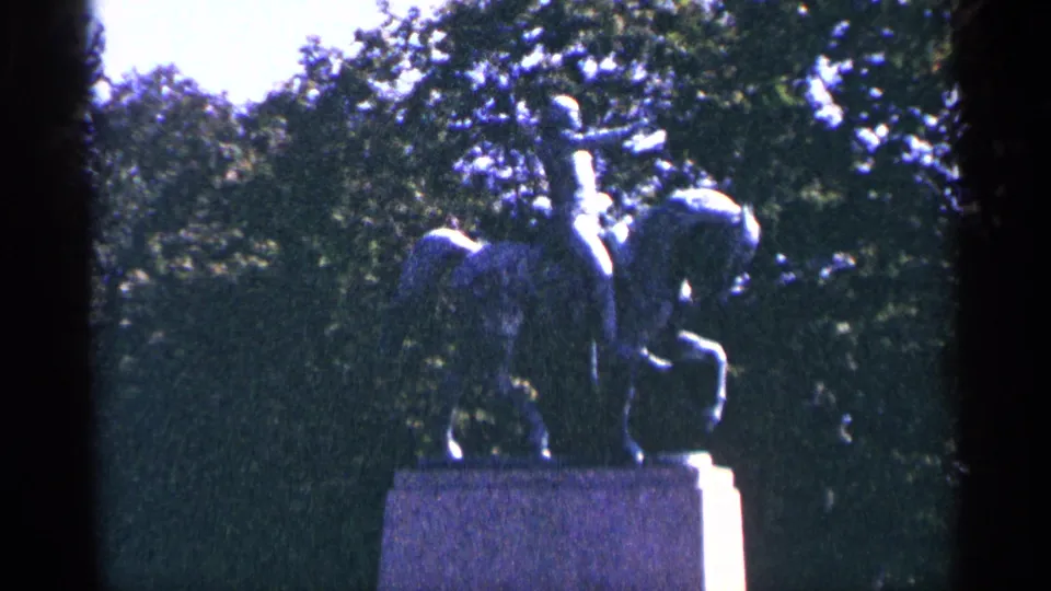 Close view of a bronze equestrian statue on a stone pedestal, filmed against dense trees in the Niagara Falls Canada area.