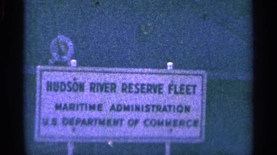 Close 8mm view of the Hudson River Reserve Fleet sign, with federal maritime text visible and soft home-movie focus.