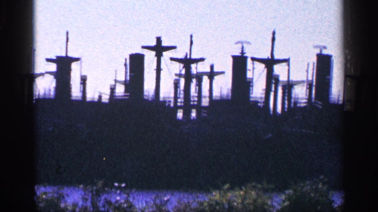 Dark ship silhouette with mast-like cross shapes against a pale sky.