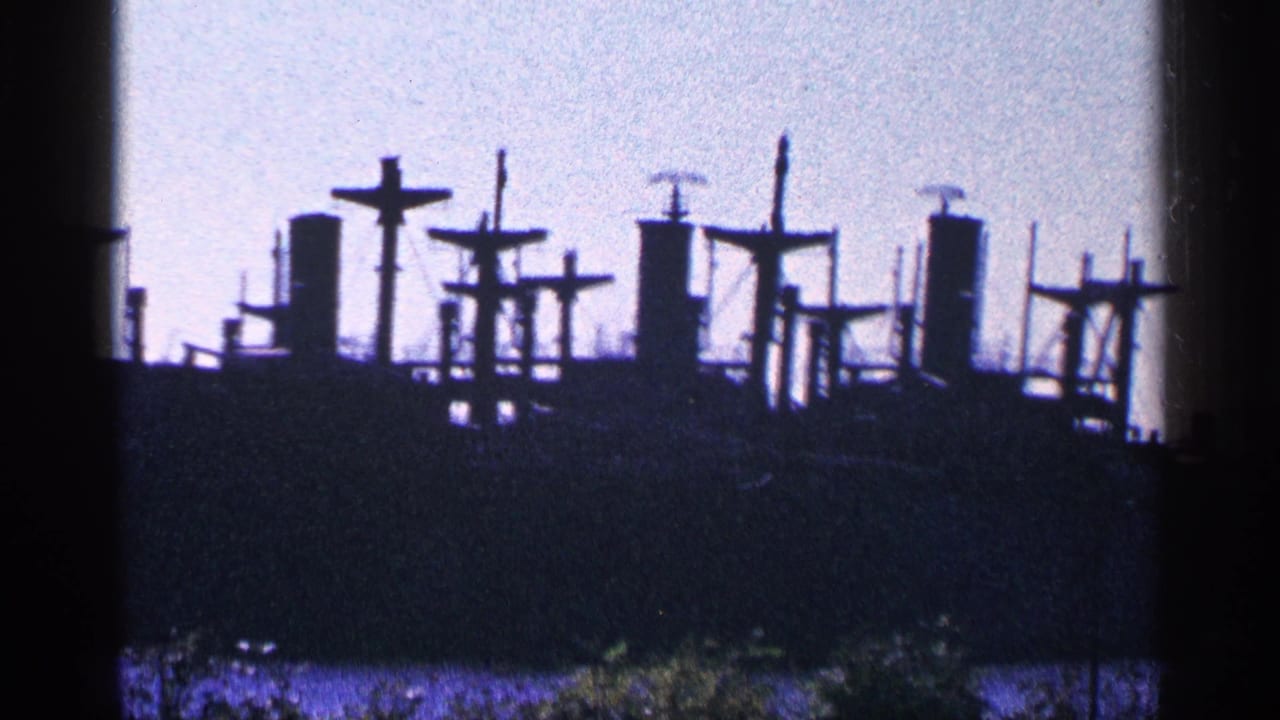 Distant vessel outline with masts and dark shoreline below a pale sky.