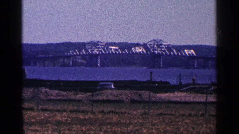 1964 8mm harbor view near Niagara Falls, Canada, with water, an open foreground, and a distant bridge-like or dockside structure.