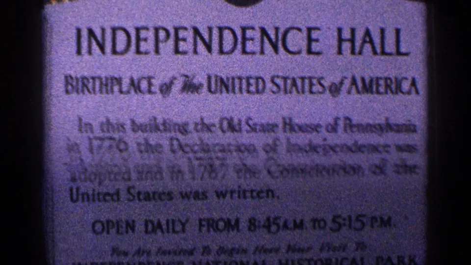 Soft-focus 8mm close-up of the Independence Hall marker, with the heading and historical text visible but partly blurred.