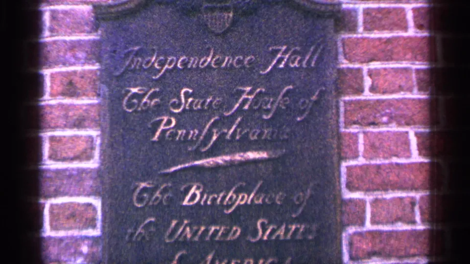 1964 Pennsylvania frame showing a dark marker on brick reading Independence Hall and Old State House of Pennsylvania.