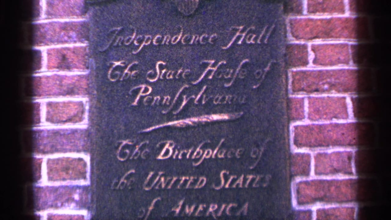 1964 Pennsylvania home-movie frame showing an Independence Hall plaque set into brickwork.