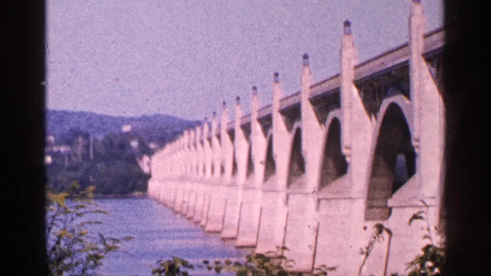Gettysburg-area bridge view on 8mm film, with pale arches receding across the river.