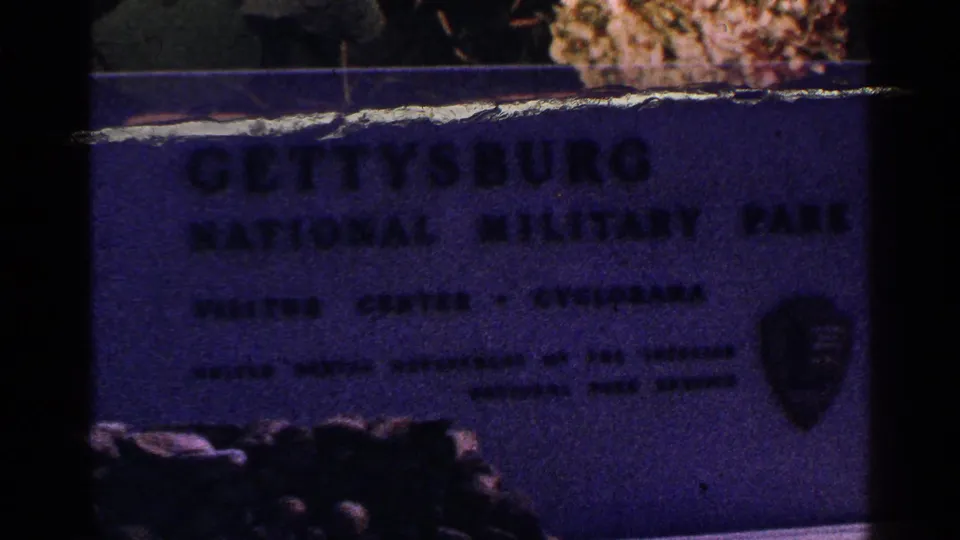 Sign for Gettysburg National Military Park visitor center seen in a soft 1964 home-movie frame.