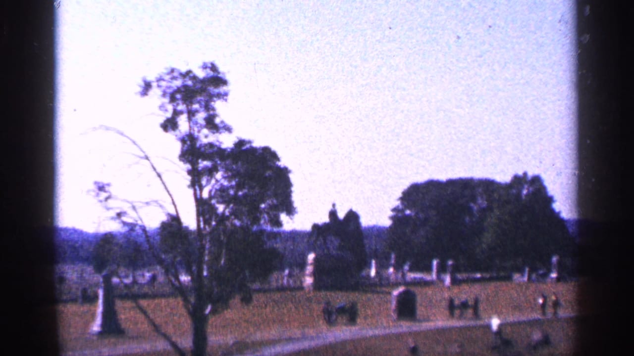 Battlefield lawn with monuments, trees, paths, and distant visitors.