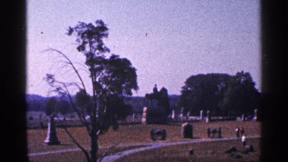Gettysburg National Military Park battlefield view in 1964, showing monuments, trees, open grass, and distant visitors.
