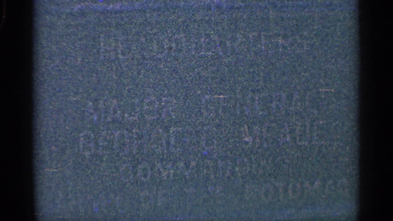 Dark blue-green film frame with heavy grain and little visible detail.