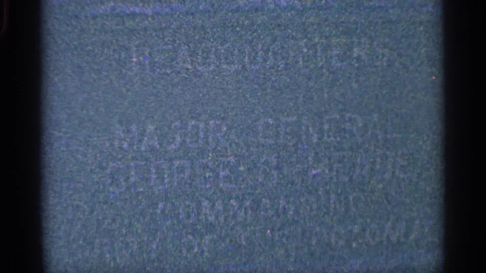 Underexposed 8mm frame showing green-blue film texture and faint marks, with no readable or identifiable scene detail.
