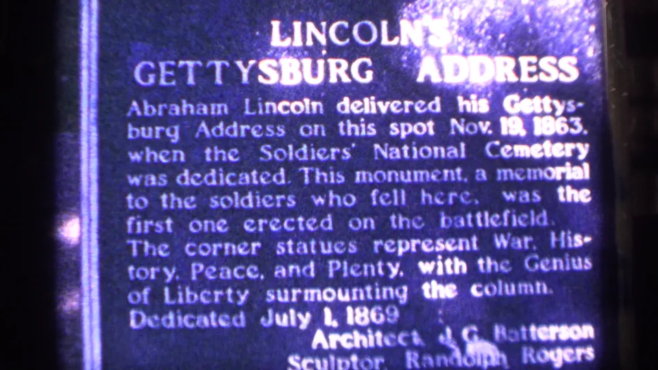 Close 1964 Pennsylvania 8mm view of a blue plaque describing Lincoln's Gettysburg Address and the cemetery monument.