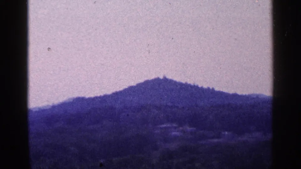 1964 Pennsylvania 8mm view of a distant wooded hill or mountain ridge, softly exposed and bordered by the film frame.