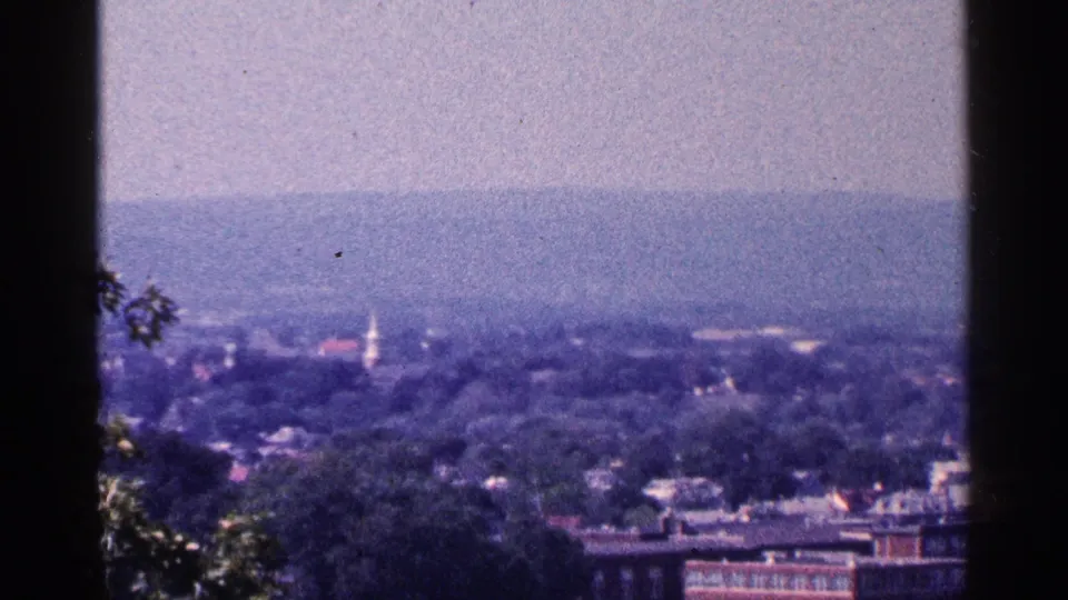 1964 Pennsylvania view over a town, with a white church steeple rising among trees and hills.