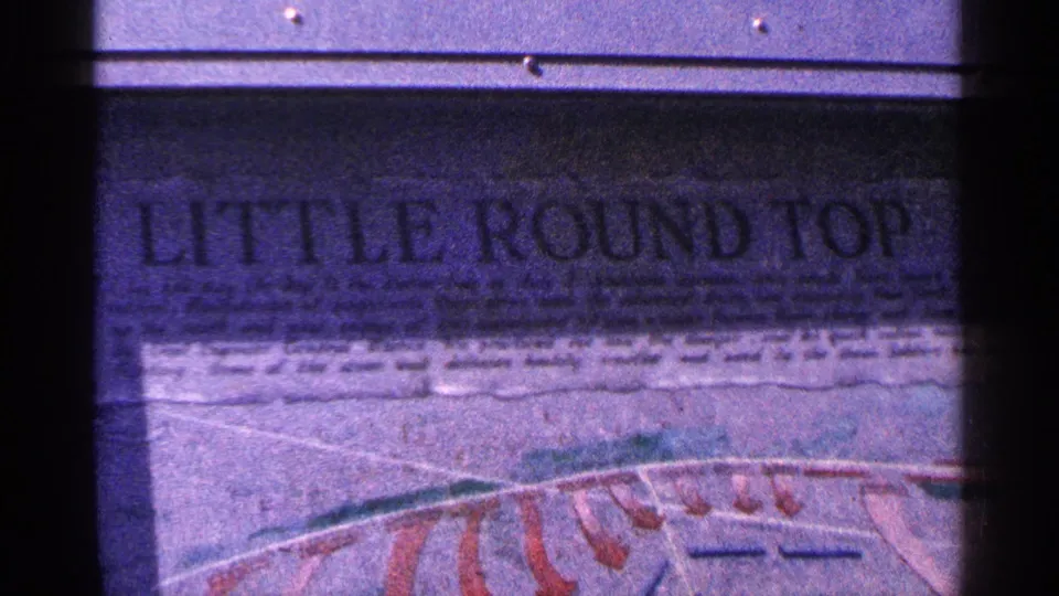 1964 Pennsylvania 8mm frame showing the Little Round Top sign close-up, including bold lettering and faded red graphic lines below.