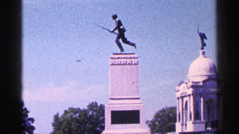 1964 Pennsylvania 8mm frame showing the First Minnesota Volunteer Regiment Monument area with a soldier statue, pedestal, trees, and domed structure.