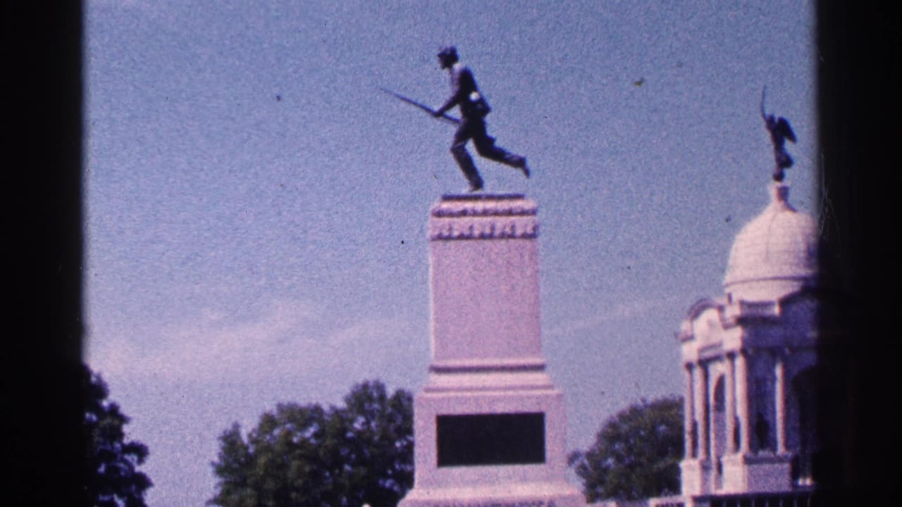 Tall monument with soldier statue and domed memorial structure framed by dark film edges.