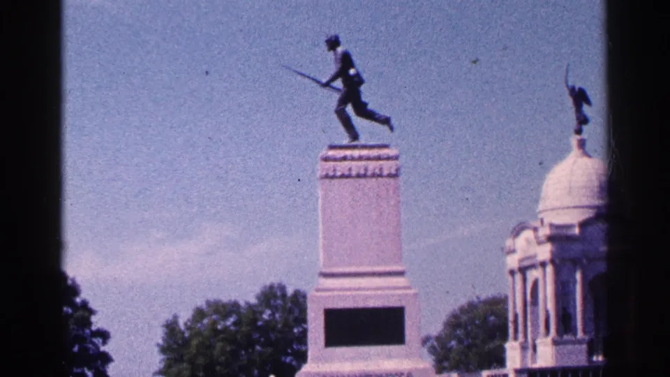 Home-movie view of the Gettysburg monument scene, with the soldier statue on a pedestal and a domed structure partly visible to the right.