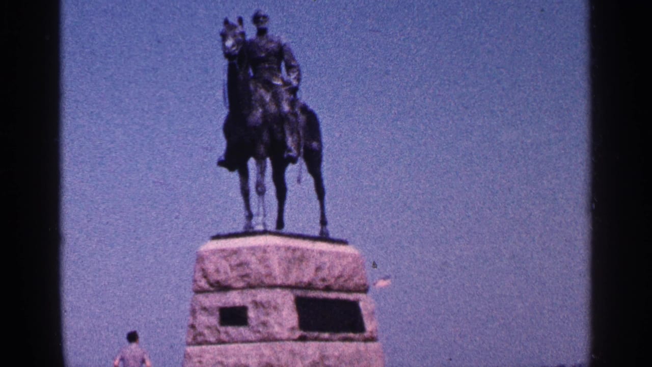1964 Pennsylvania 8mm frame showing a bronze equestrian statue on a large stone base with a small visitor near the bottom edge.