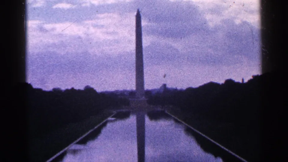 1964 Washington, D.C. home-movie frame showing the Washington Monument, Reflecting Pool, and shadowed foreground edges.
