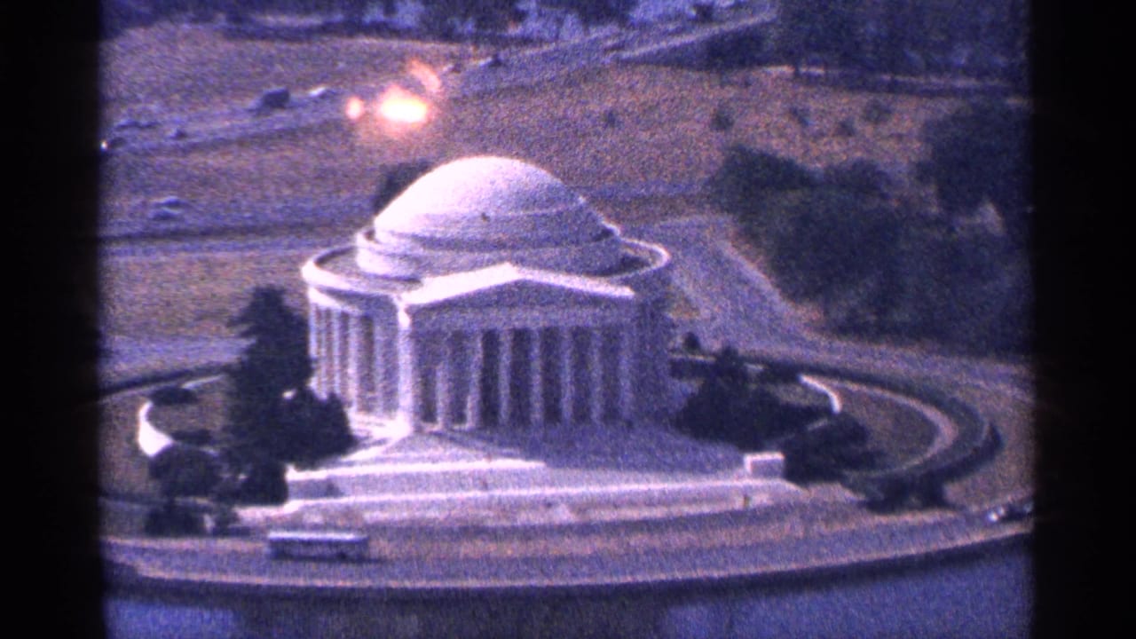 Aerial view of the Jefferson Memorial beside water with roads and trees nearby.