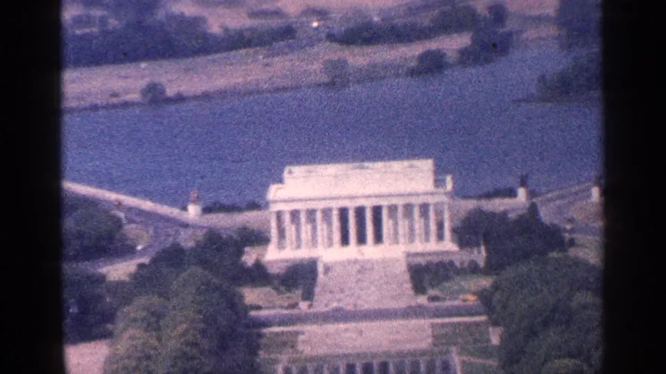 1964 Washington DC aerial home-movie view of the Lincoln Memorial, framed by trees, paths, and water in soft small-gauge film color.