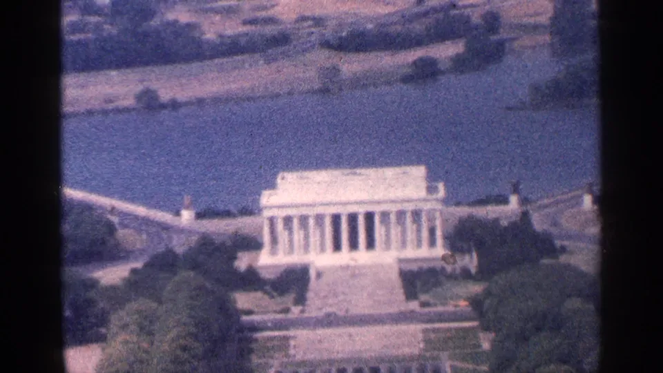 1964 8mm aerial view of the Lincoln Memorial in Washington, DC, with the Reflecting Pool area, trees, and roadway visible.