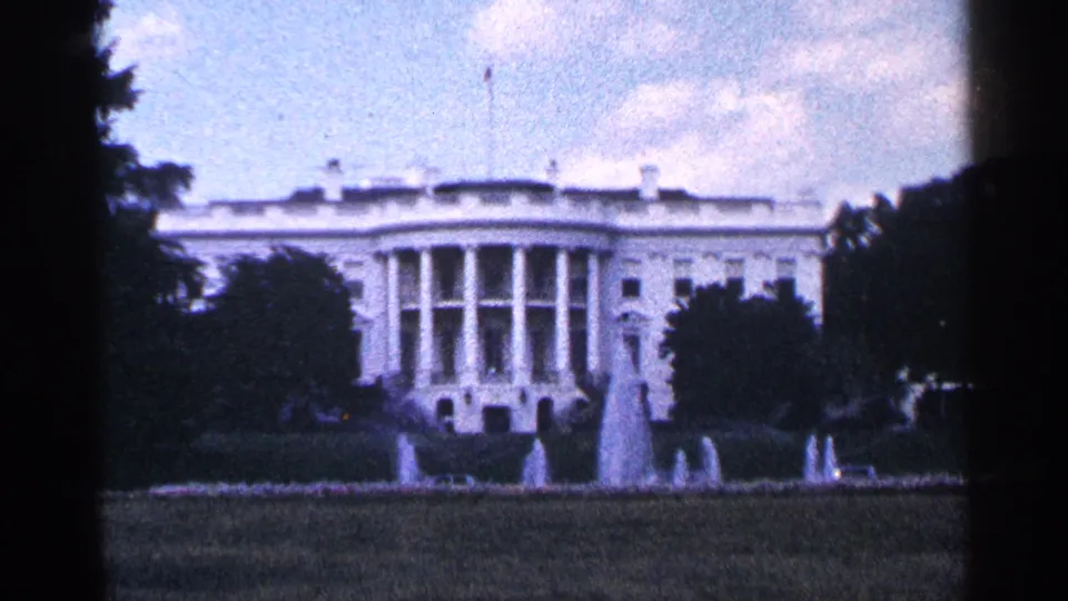 1964 Washington DC home-movie frame of the White House, with trees at the sides, lawn below, and fountains in the foreground.
