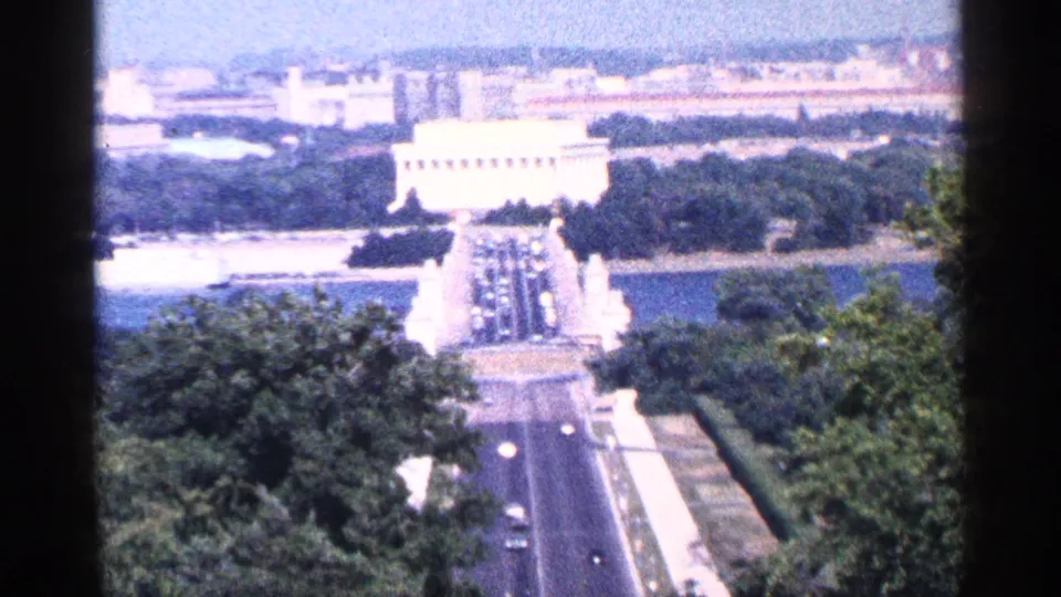 1964 Washington, DC 8mm frame looking over trees, roads, water, and a distant monument area from an elevated viewpoint.