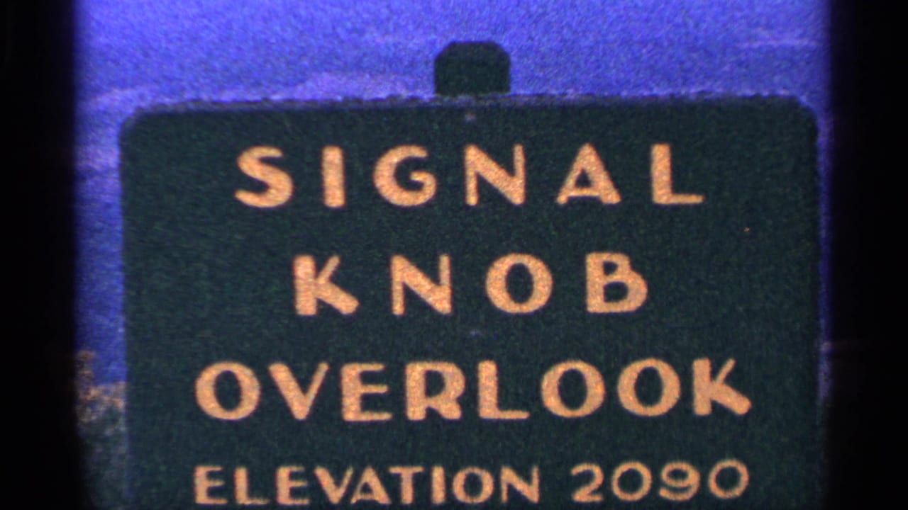 1964 8mm frame showing a green Signal Knob Overlook sign with gold lettering and elevation 2090 visible near the bottom.