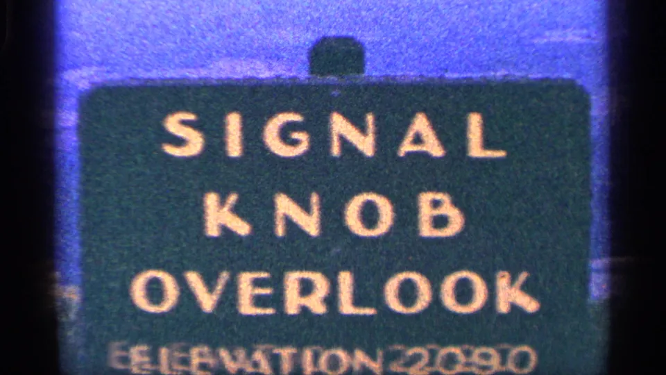 1964 8mm frame showing a tight, slightly soft crop of the Signal Knob Overlook sign and its elevation marking.